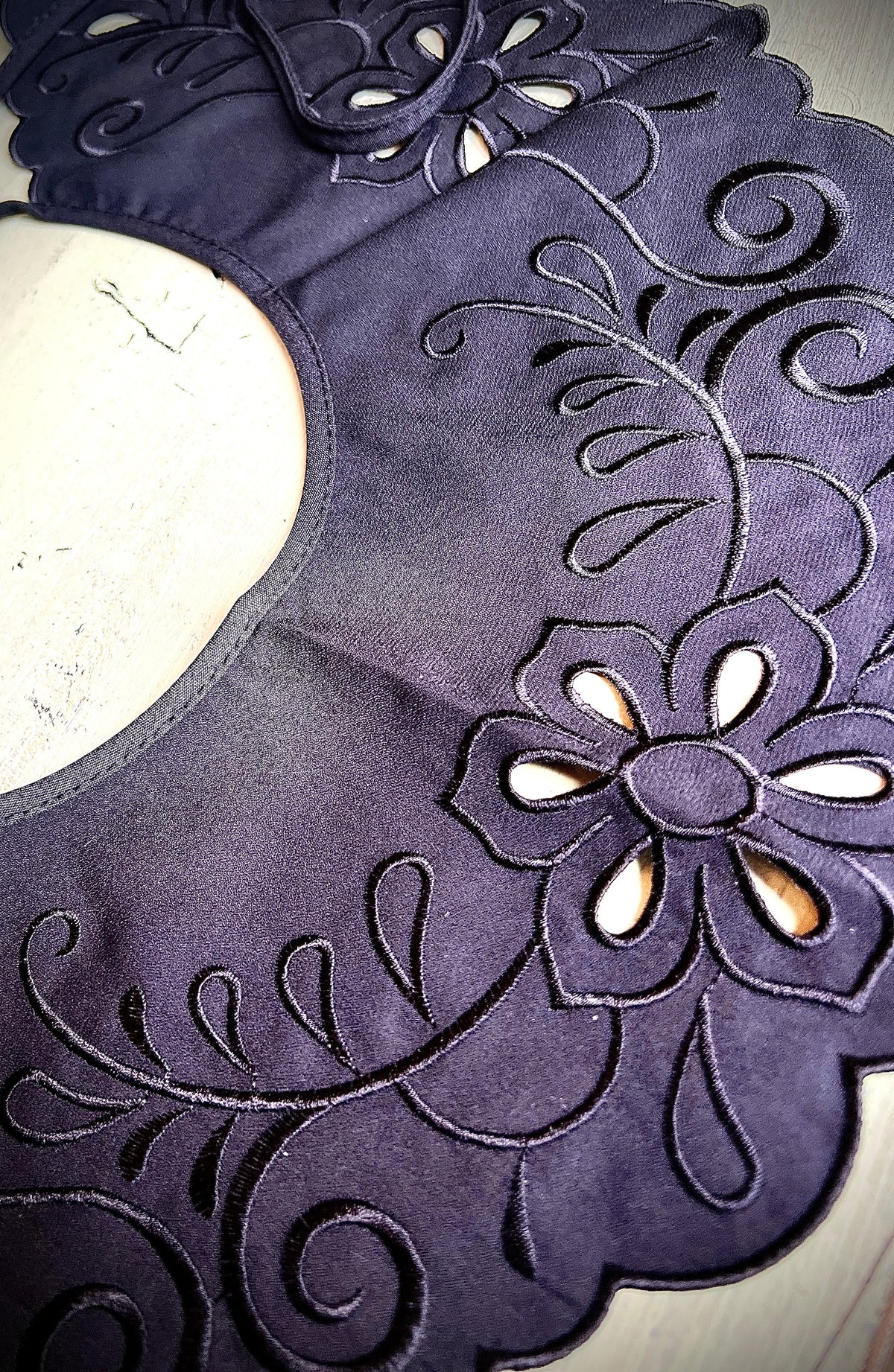 A large black map-like collar is sewn by hand