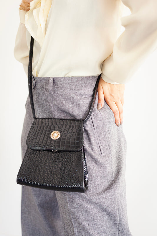 A small evening bag made of lacquer with a long strap