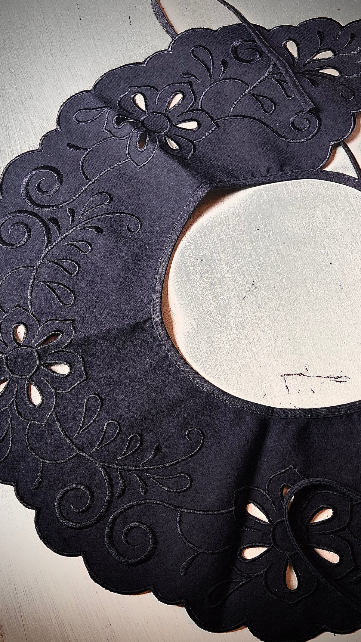 A large black map-like collar is sewn by hand