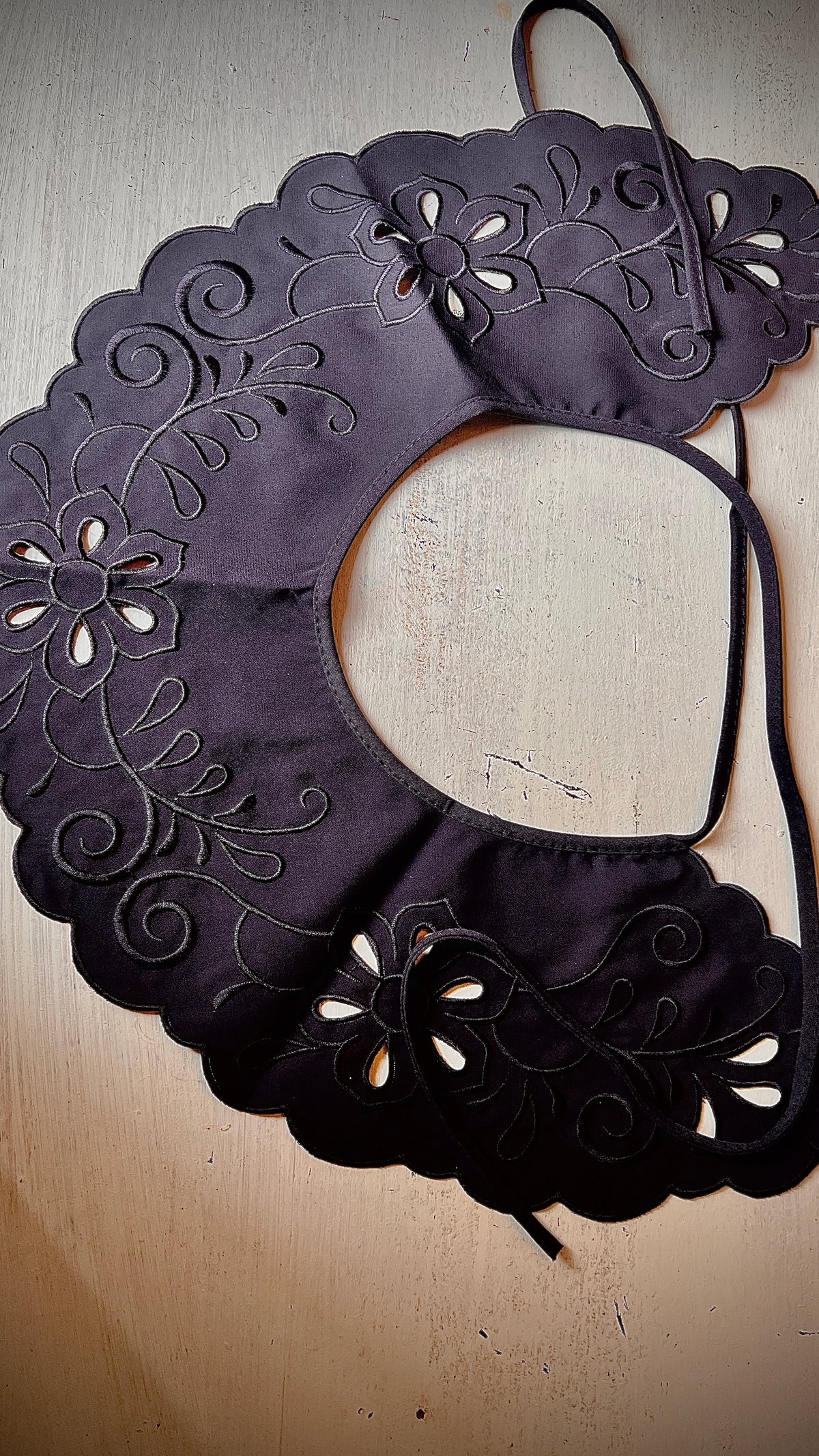 A large black map-like collar is sewn by hand