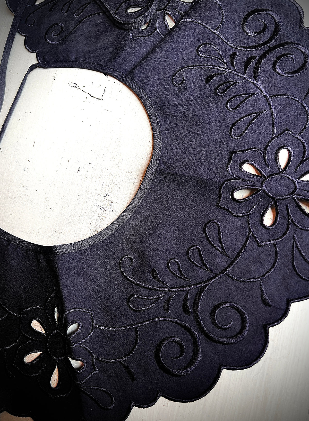 A large black map-like collar is sewn by hand