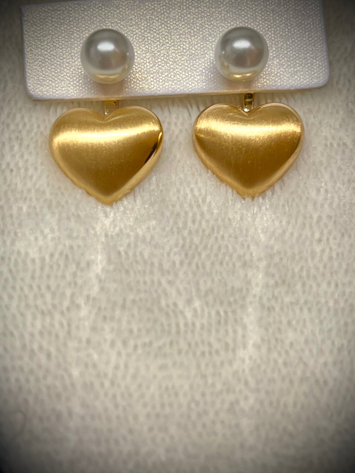 Gold heart earrings combined with a pearl